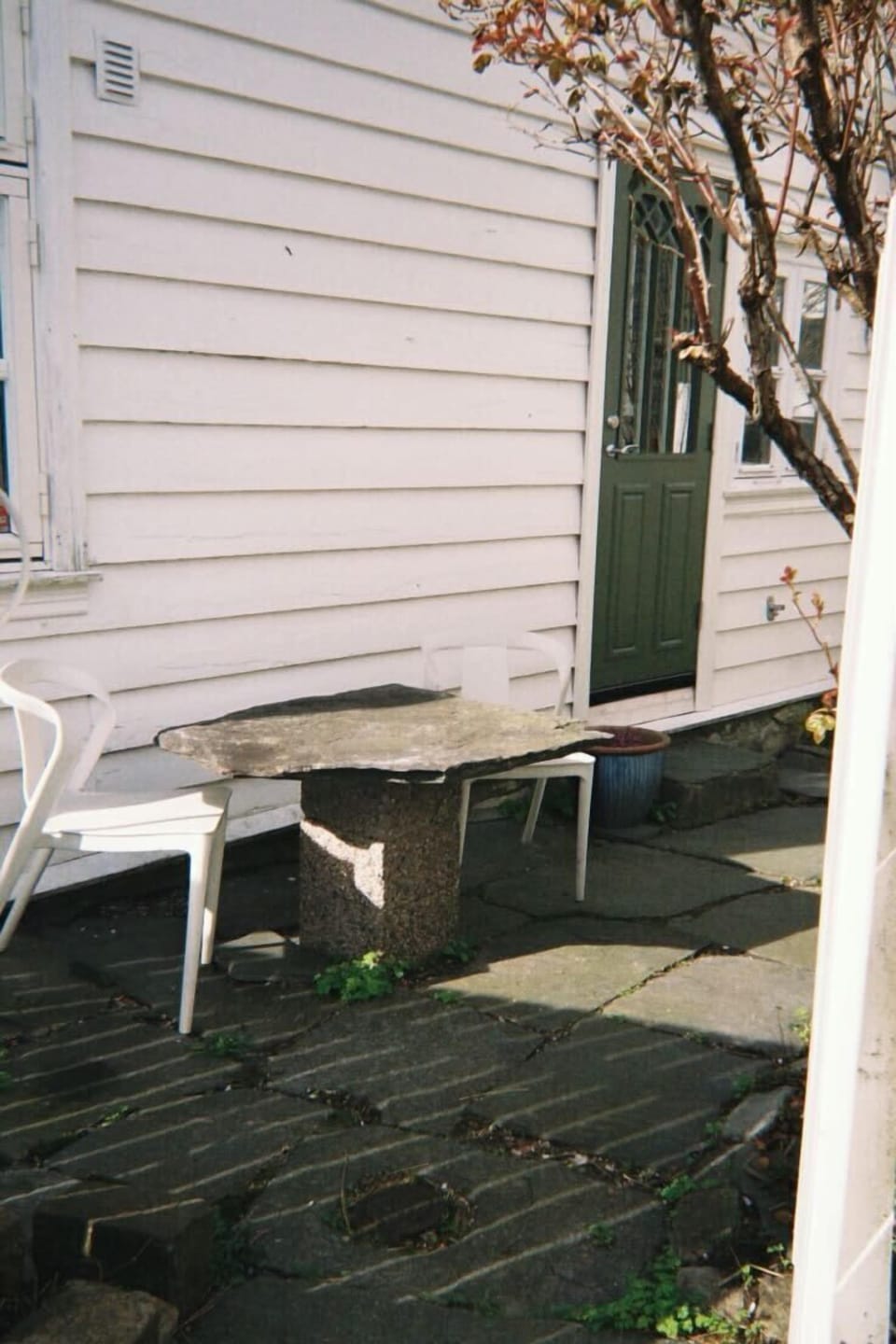Outdoor patio space with a natural stone table and chairs, bathed in sunlight.