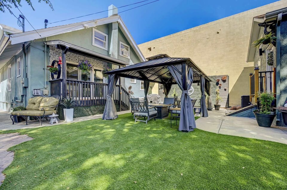 Covered pergola with soft curtains and outdoor seating—grab a cold drink, kick off your shoes, and let the kids play on the bright green lawn while the homes frame this private hangout spot. Perfect for slow mornings outside and easy group catch-ups.