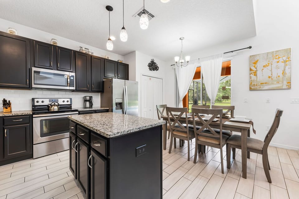 Cook and connect in a fully equipped kitchen with stainless-steel appliances, a spacious dining table, and open access to the living area — perfect for family meals together.