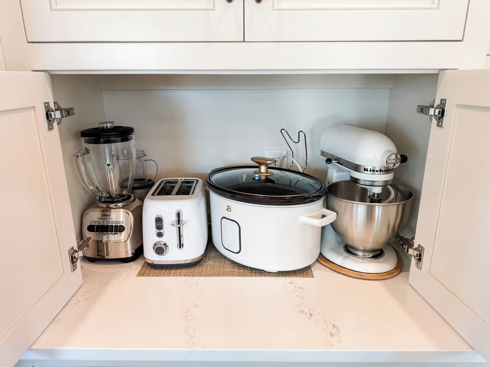 Small appliances located behind doors next to the refrigerator.