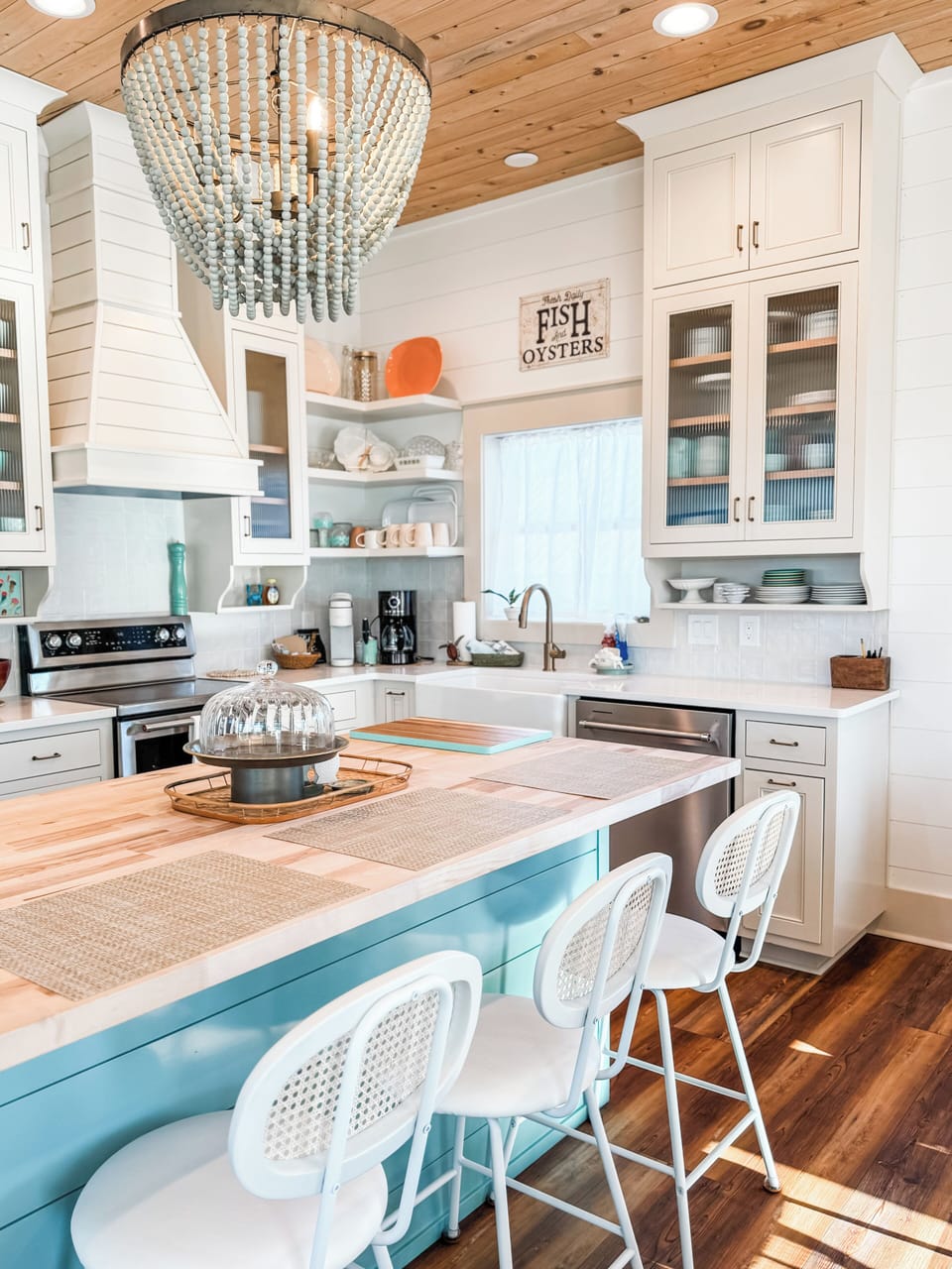 Kitchen with island and 3 barstools, open to dining and living rooms