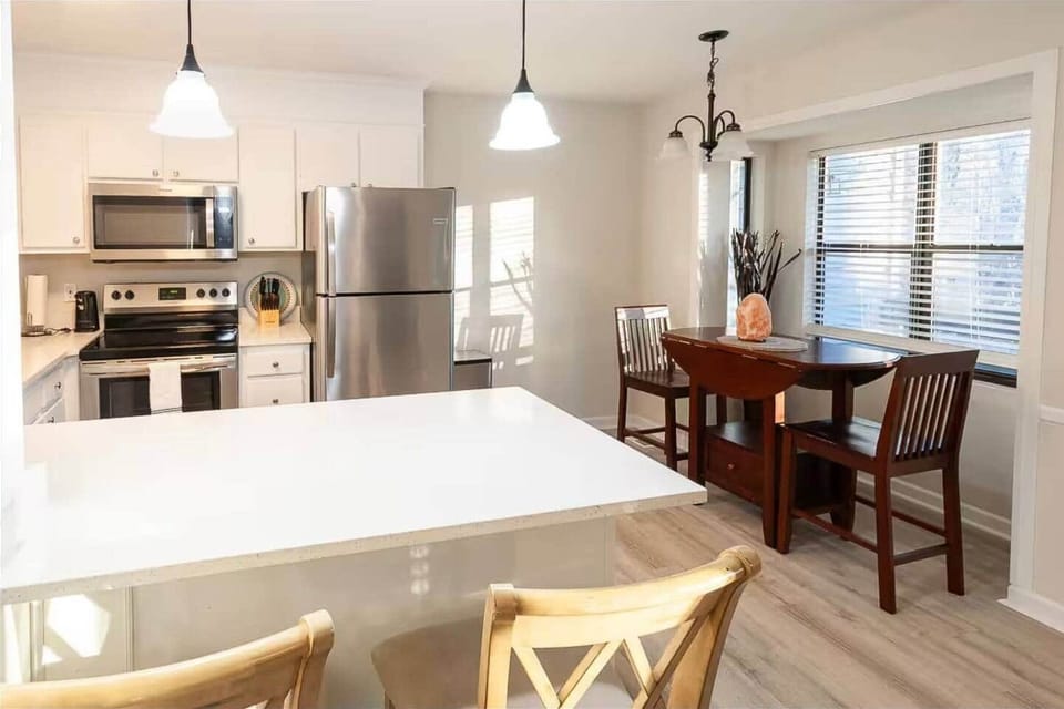 This fully equipped kitchen features stainless steel appliances, a large counter with seating, and a cozy dining nook framed by natural light. Whether you’re cooking a full meal or enjoying takeout, this space is perfect for gathering and dining in.