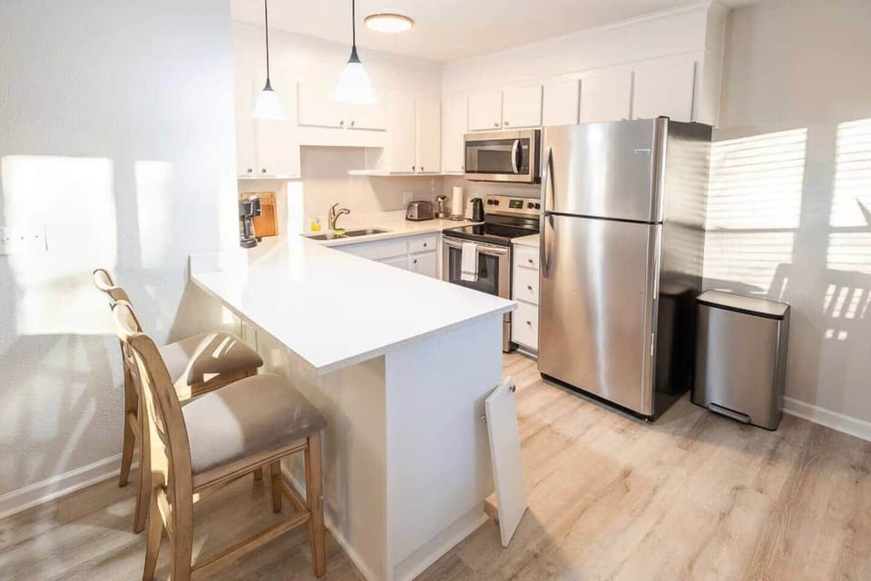 This bright, modern kitchen includes stainless steel appliances, quartz countertops, and a breakfast bar with seating for two. Fully stocked with cooking essentials, it’s perfect for everything from morning coffee to home-cooked meals.