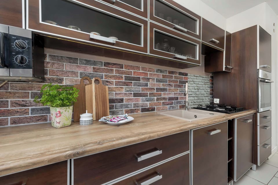The kitchen decorated in brown color and wooden countertop with gas stove, microwave oven, set of dishes and cutlery will allow you to prepare tasty dishes, and the dishwasher will be helpful for quick cleaning.