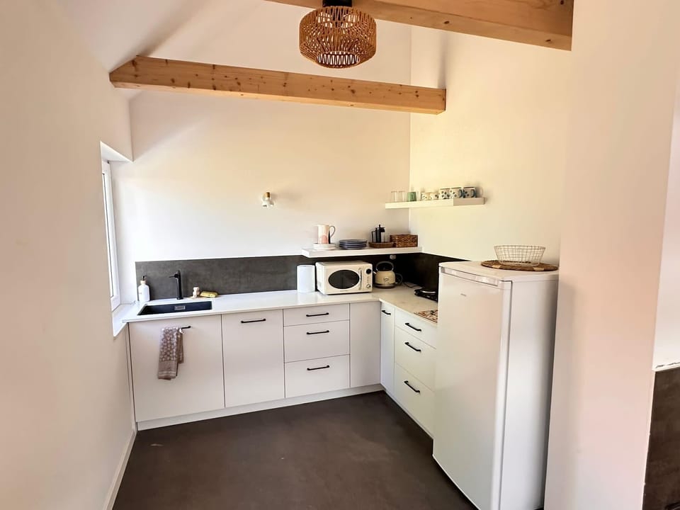 A compact and functional kitchen with white cabinets and a window above the sink. Equipped for preparing simple meals.