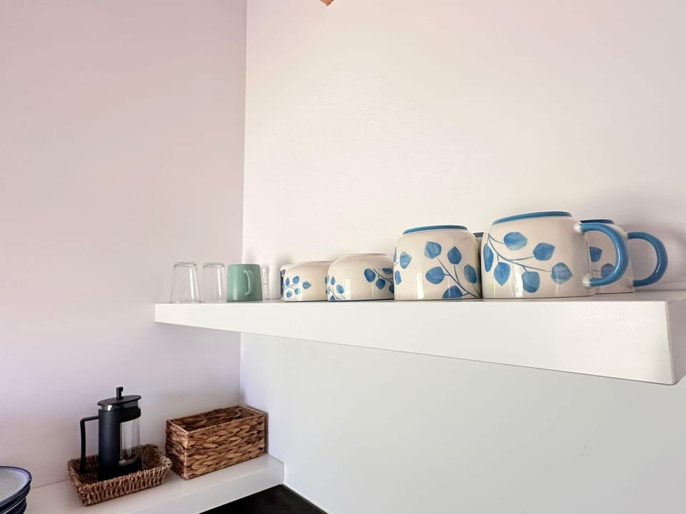 A kitchen shelf displaying a neat row of ceramic mugs and bowls. A touch of charm and organization.