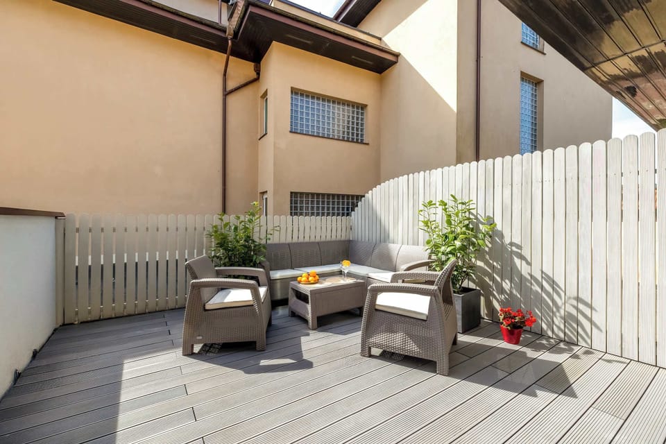 A small patio furnished with outdoor chairs and a table. Potted plants add greenery and privacy. The area feels perfect for relaxing outdoors.