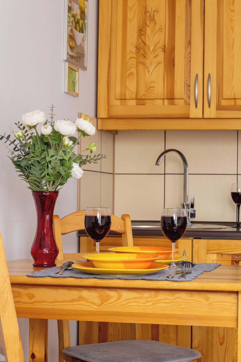A close-up of the dining table presents a stylish display with wine glasses and a bowl of fresh oranges as decorative elements.