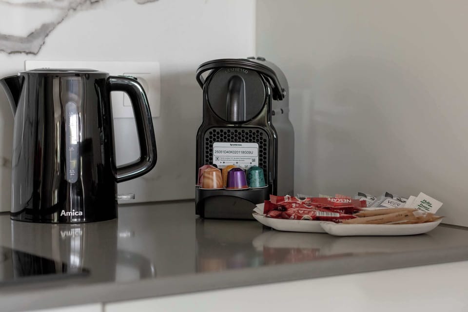A coffee and tea station with a kettle, espresso machine, and mugs. Perfect for morning rituals or an afternoon break.