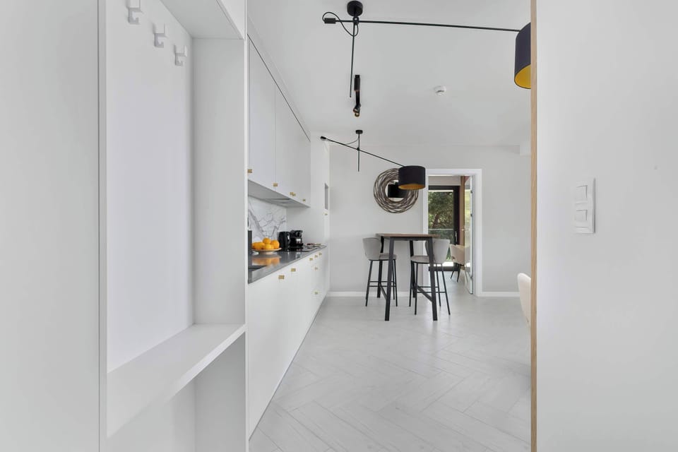 A bright hallway with white cabinetry and a view into the dining area. Light flooring enhances the spacious, clean design.