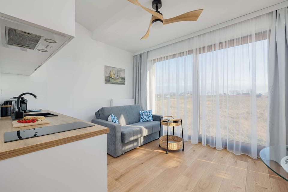 A modern living room with an open kitchen, featuring a stylish blue and white interior.