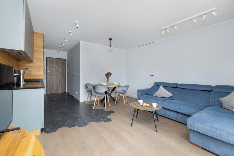 Living and dining area with a round table, modern gray sofa, and floor-to-ceiling curtains.