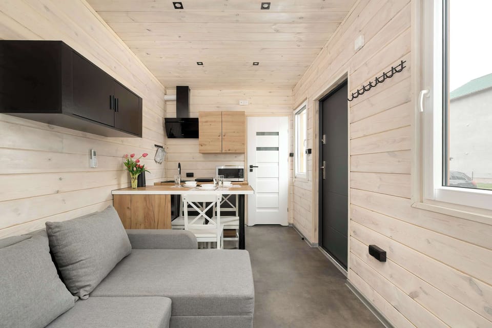 Living area with gray L-shaped sofa, wall-mounted TV, and open access to the dining space.
