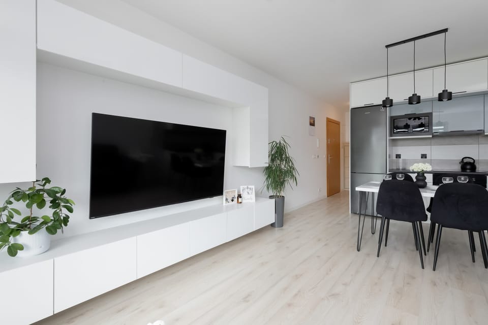 White walls with a large TV and green flowers that add to the coziness of the interior.