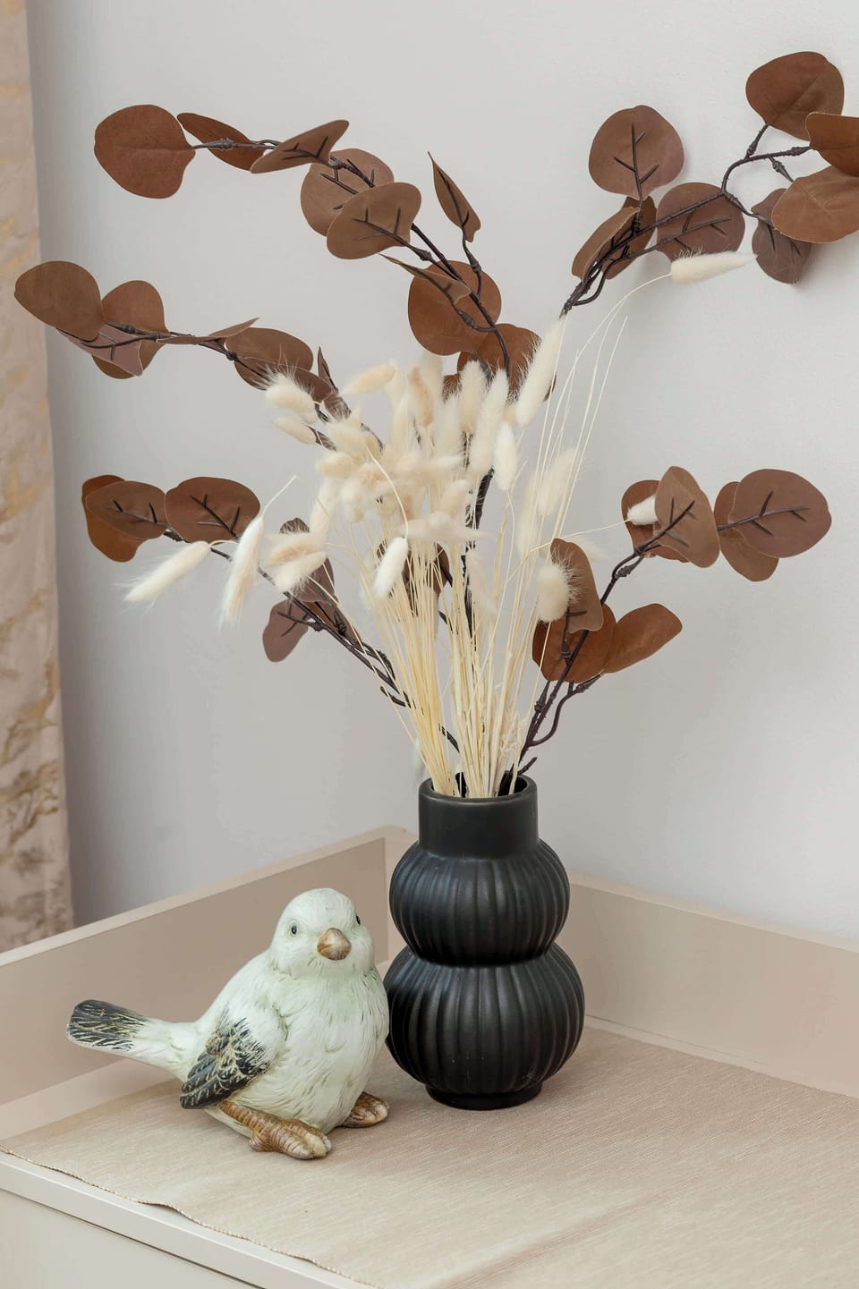A stylish table with a black vase and dried flowers. The minimalist decor adds warmth and texture to the space.