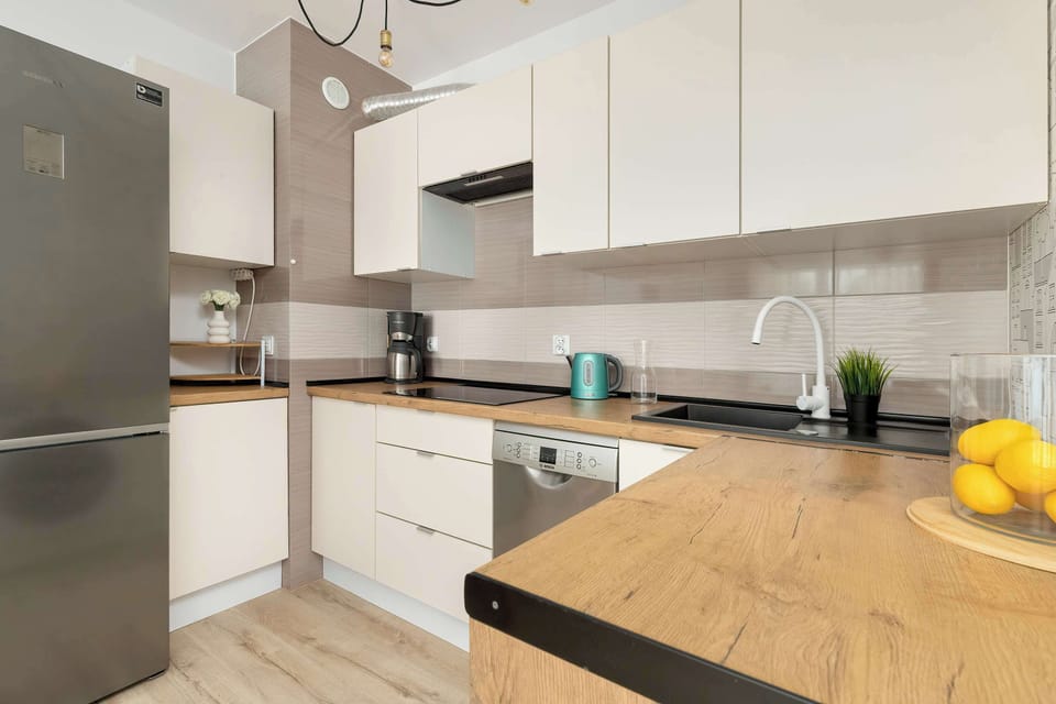 A compact kitchen with modern appliances and sleek white cabinetry. Perfect for preparing everyday meals.