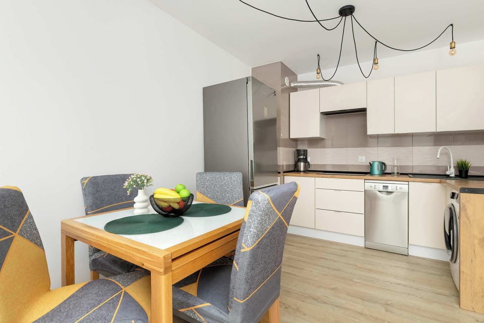 A modern kitchen with a dining table and a stylish pendant light. The space is compact and functional, with plenty of counter space.