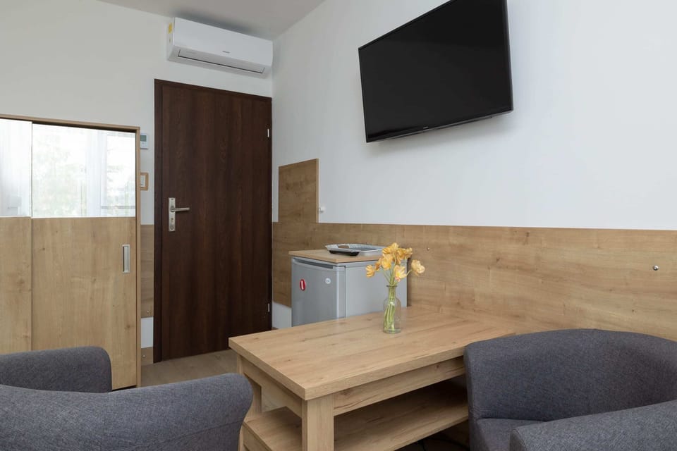 Welcoming living area with a wooden coffee table, a flat-screen television, and two armchairs.