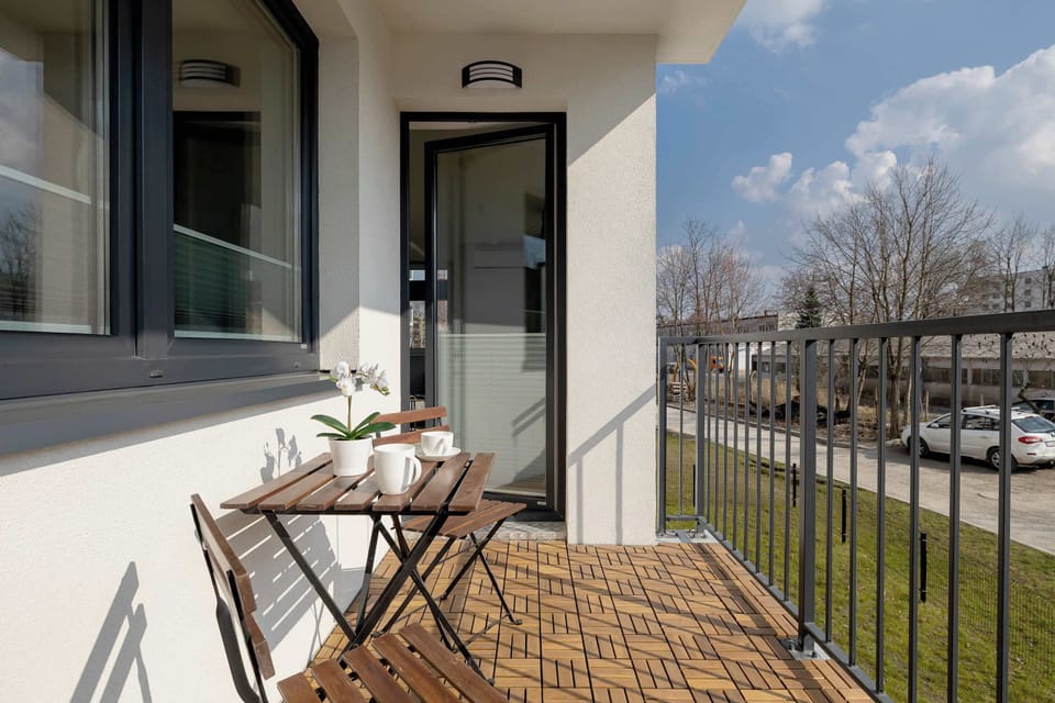 A second angle of the cozy balcony with a table and chairs for outdoor dining. The fresh air and surrounding greenery make it an ideal retreat.

