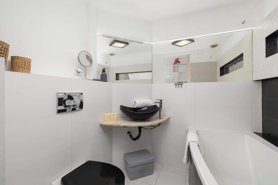 Stylish and elegant bathroom with towels, welcoming toiletries set, and bathtub.