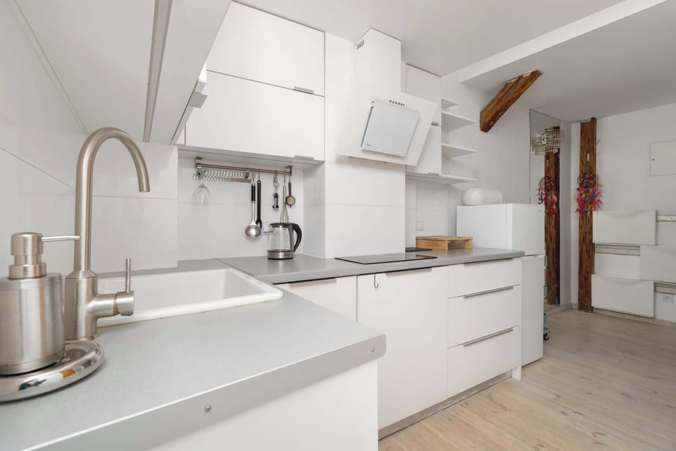 White and functionally equipped kitchen with a microwave, an induction hob, and a fridge.