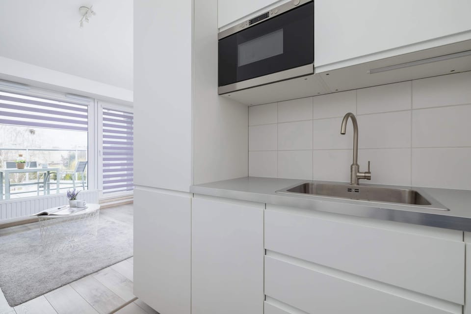 A modern and functional kitchen with a built-in oven and sleek white cabinets. The minimalist design ensures a clean and organized cooking space.
