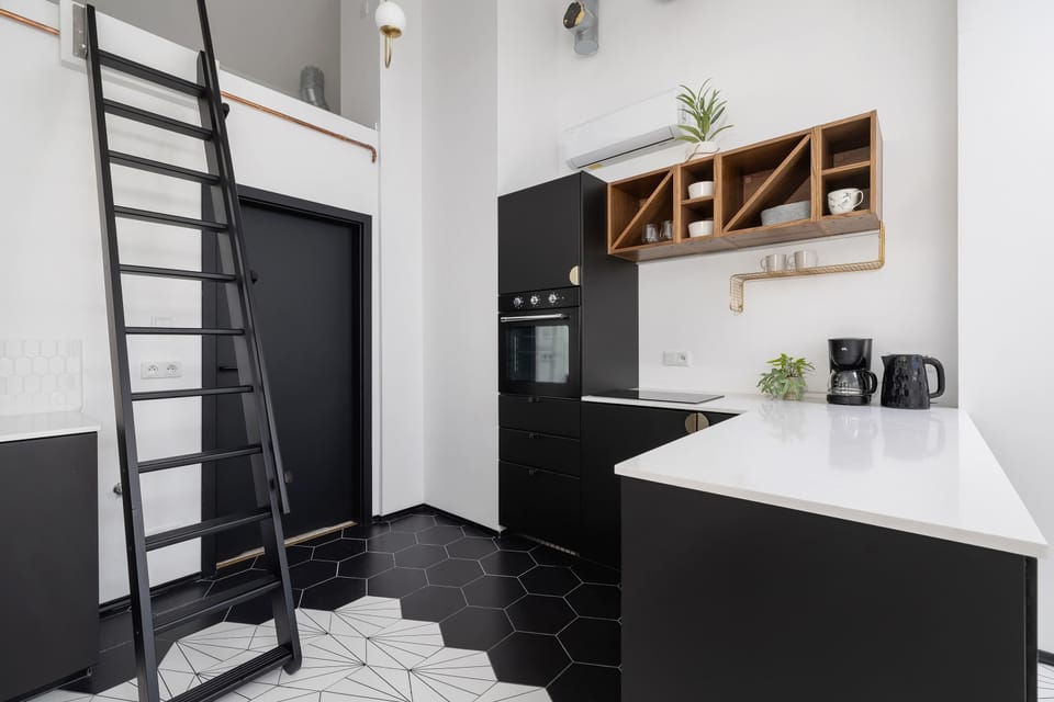 View of the kitchen and mezzanine stairs, showing black cabinetry and wooden shelves.