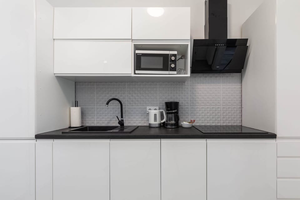 A compact yet functional kitchen with all necessary appliances, blending style and practicality.

