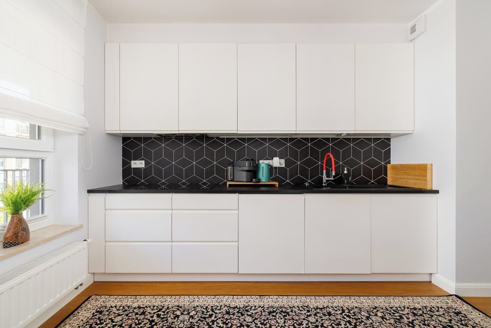 Functionally equipped, white kitchenette with a toaster, an oven, a microwave and a capsule coffee machine.