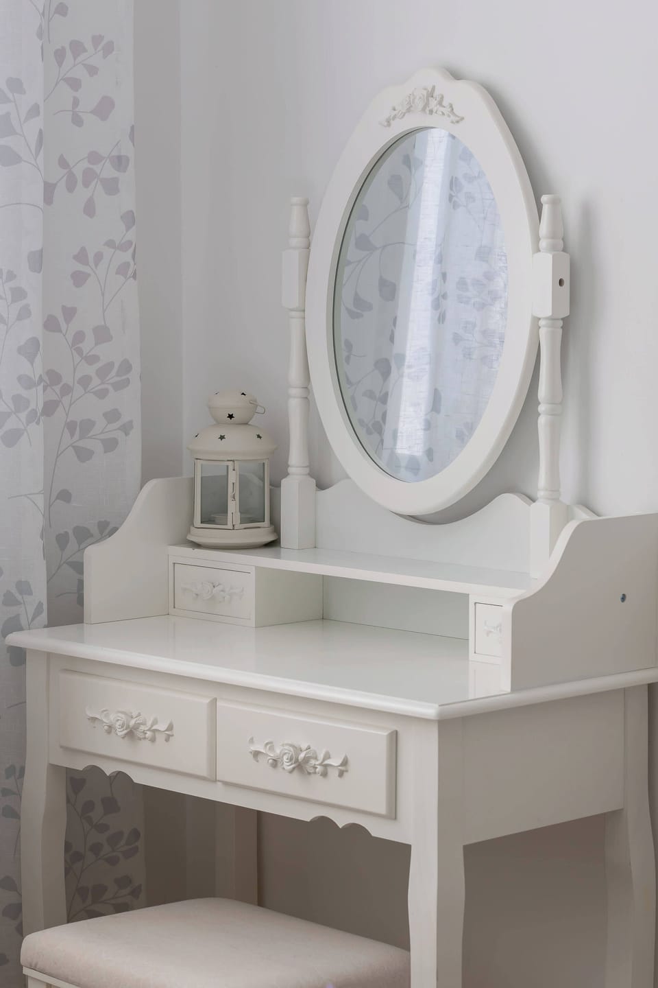 A vanity table with a circular mirror, drawers, and a small stool. The setup is simple and elegant, ideal for a bedroom corner.