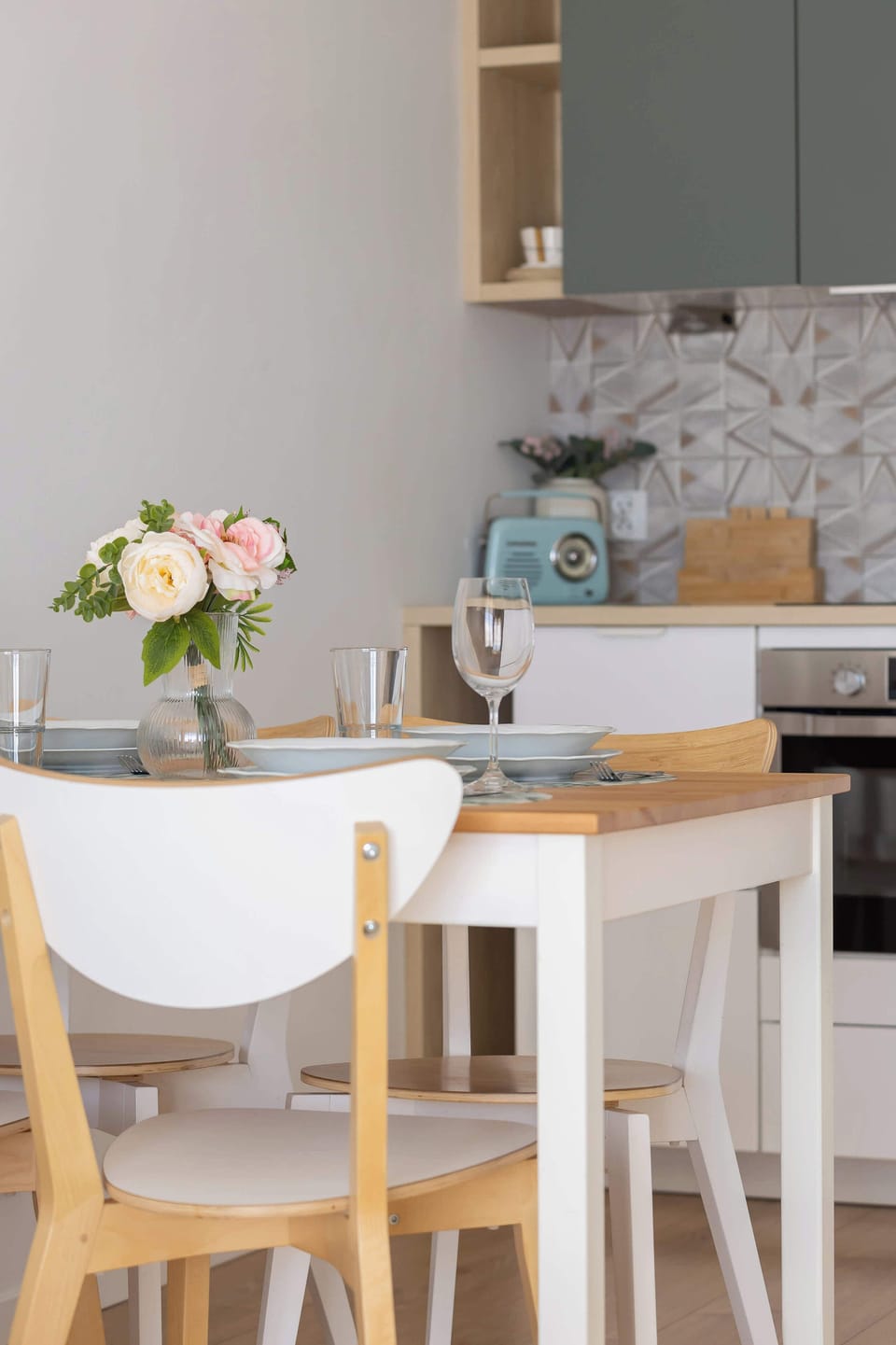  wooden dining table with Scandinavian-style chairs and a vase of fresh flowers, adding warmth and a natural touch to the minimalist space.