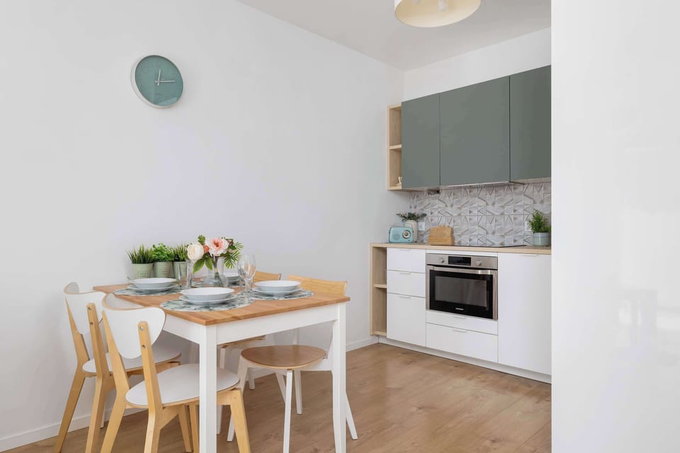 A compact kitchen space featuring a dining area with a wooden table and chairs. The walls are a light shade, creating a bright and inviting atmosphere.