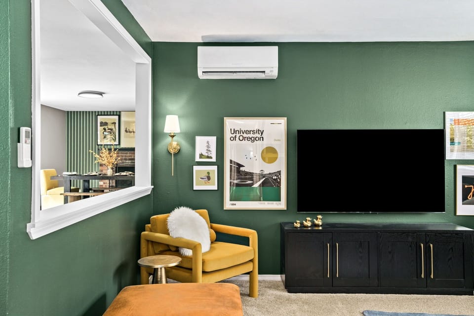 Inviting living room with sectional sofa, ottoman, chairs, and 65" smart TV. 