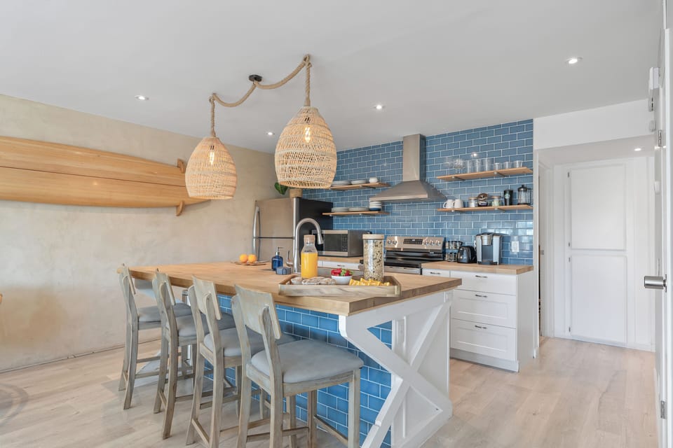 Unit A modern kitchen with barstool seating and stainless steel appliances.