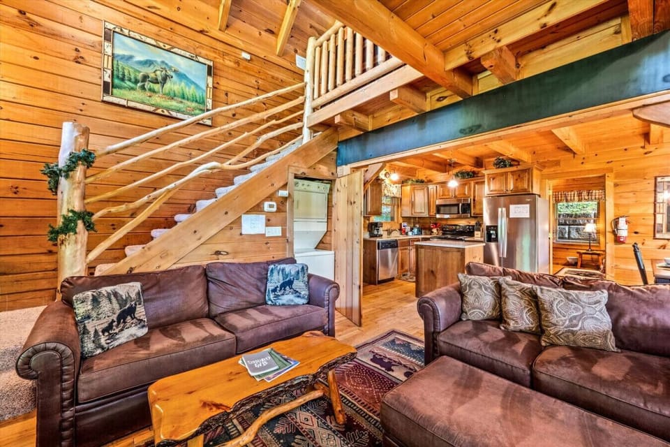 Natural light pours in through the windows and upper clerestory glass, highlighting the high ceilings and open beams that give this room its grand yet cozy feel.