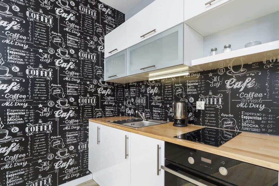A kitchenette with white furniture fronts and a black wall. 