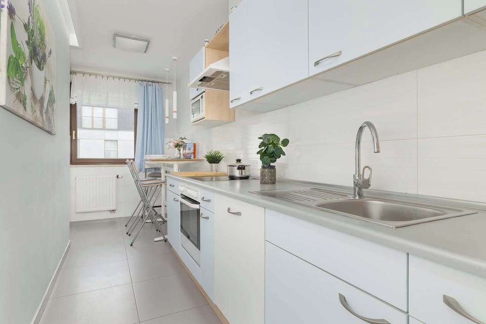 Fully equipped kitchen with electric cooktop, refrigerator with freezer, oven, microwave oven, electric kettle, dishwasher and dining area.