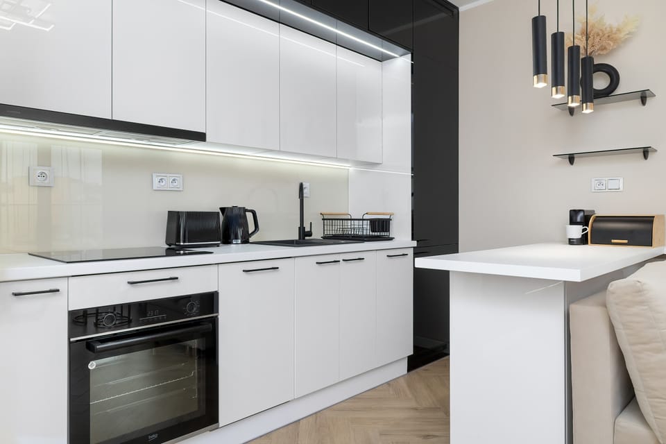 A spacious kitchen with a marble-style backsplash, white cabinets, and open shelving.