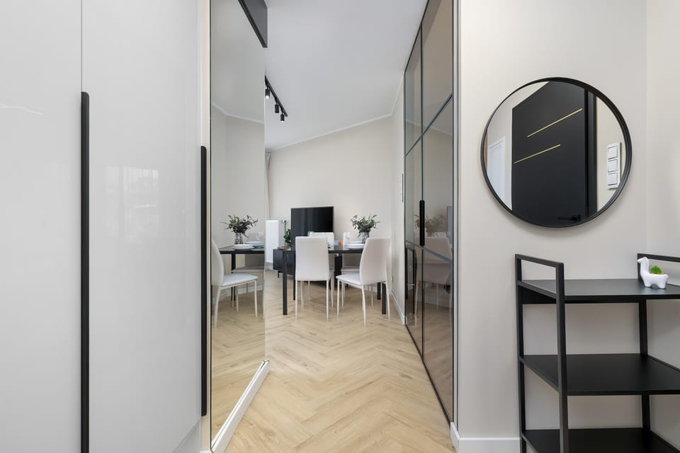 A hallway with a minimalist console table, mirror, and decorative accents leading into the apartment.