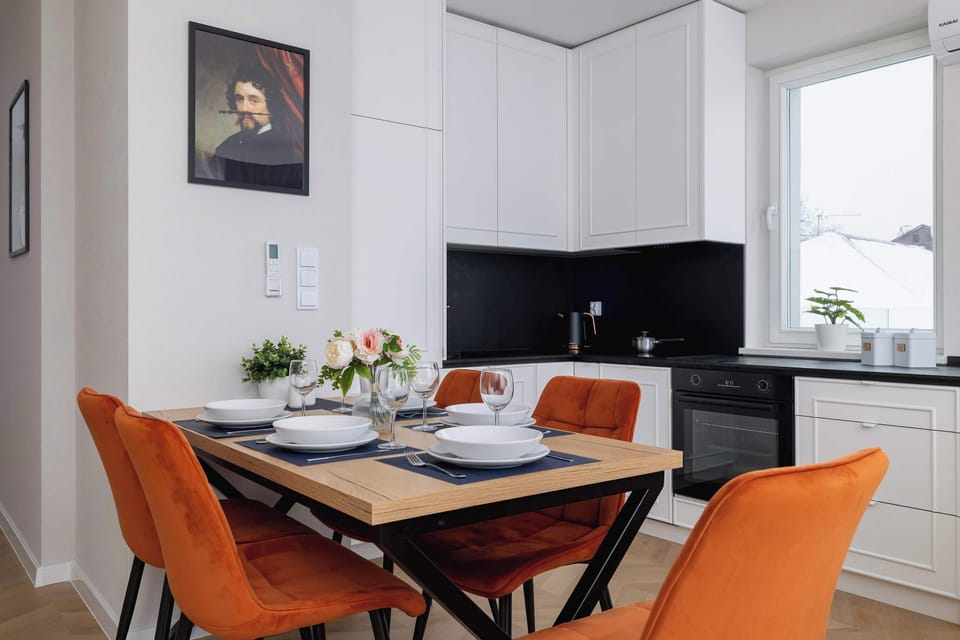 A dining area featuring a wooden table surrounded by orange chairs. The room is adjacent to the living area, providing a harmonious space for meals and entertainment.