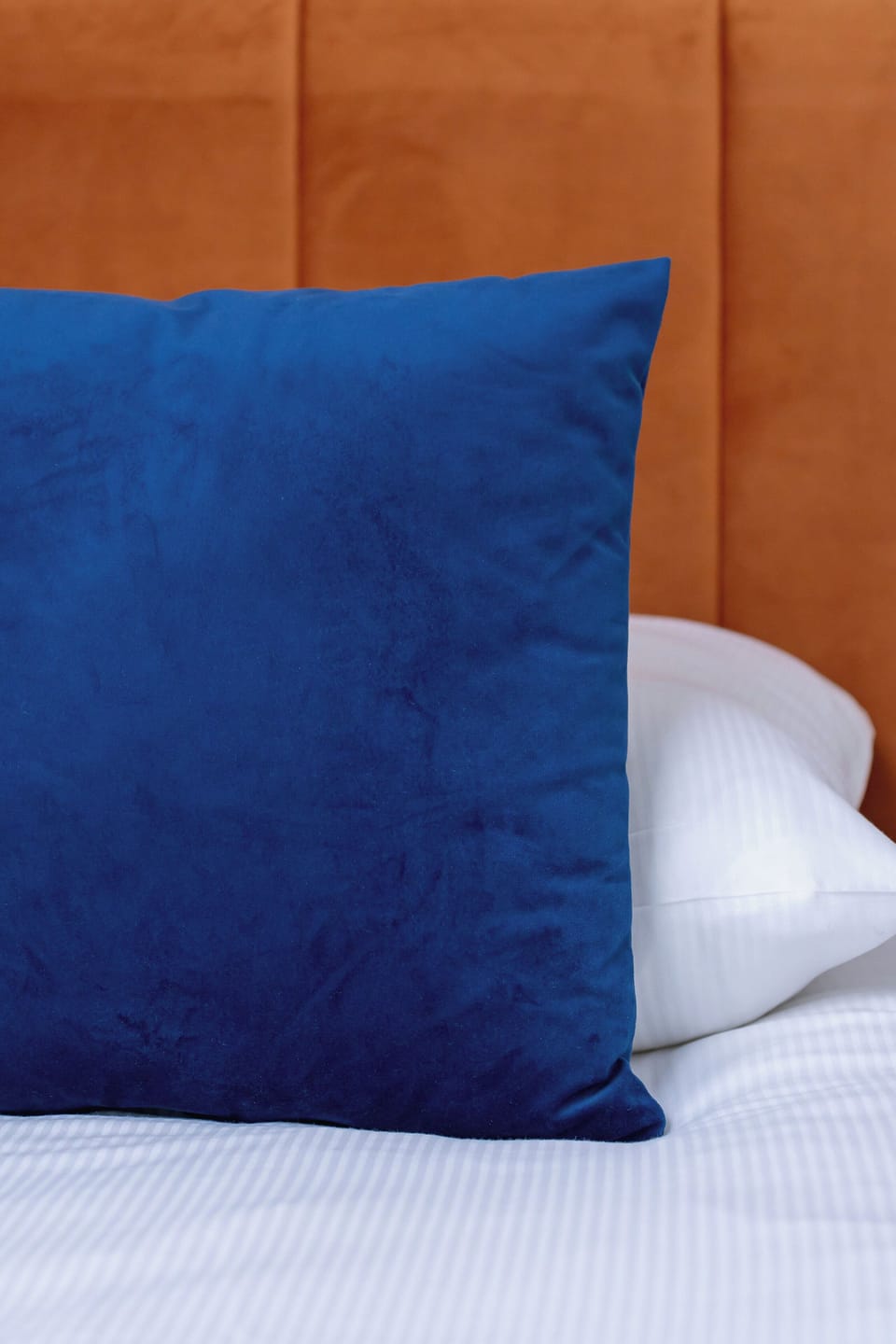A decorative blue pillow adding a pop of color and comfort to the bedroom setting. It contrasts beautifully with the neutral tones of the room.