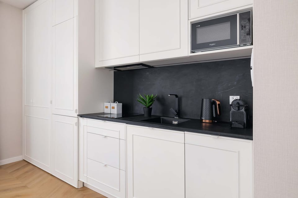 The modern kitchenette with white furniture is a functional space that enhances the comfort of the stay.