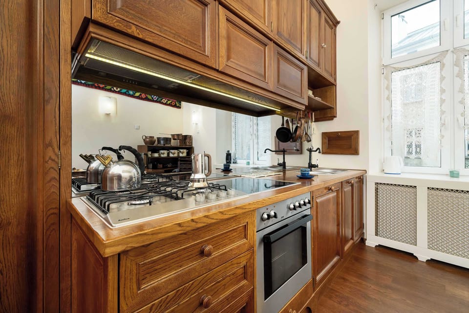 Wooden, independent kitchen with an oven, a stove, and a capsule coffee machine.