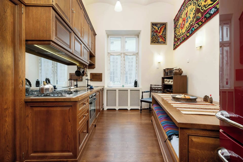 Separate, wooden kitchen with such appliances as washing machine, stove, oven and capsule coffee machine.