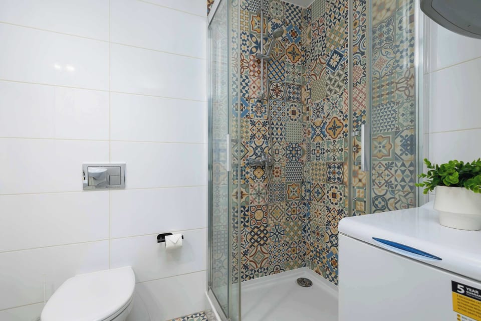 Comfortable and functional bathroom with shower, hair dryer, washing machine, towels and toiletries set.