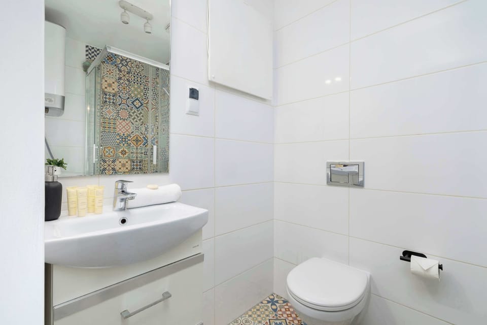 Bright bathroom with welcoming toiletries set, mirror, hair dryer and shower.