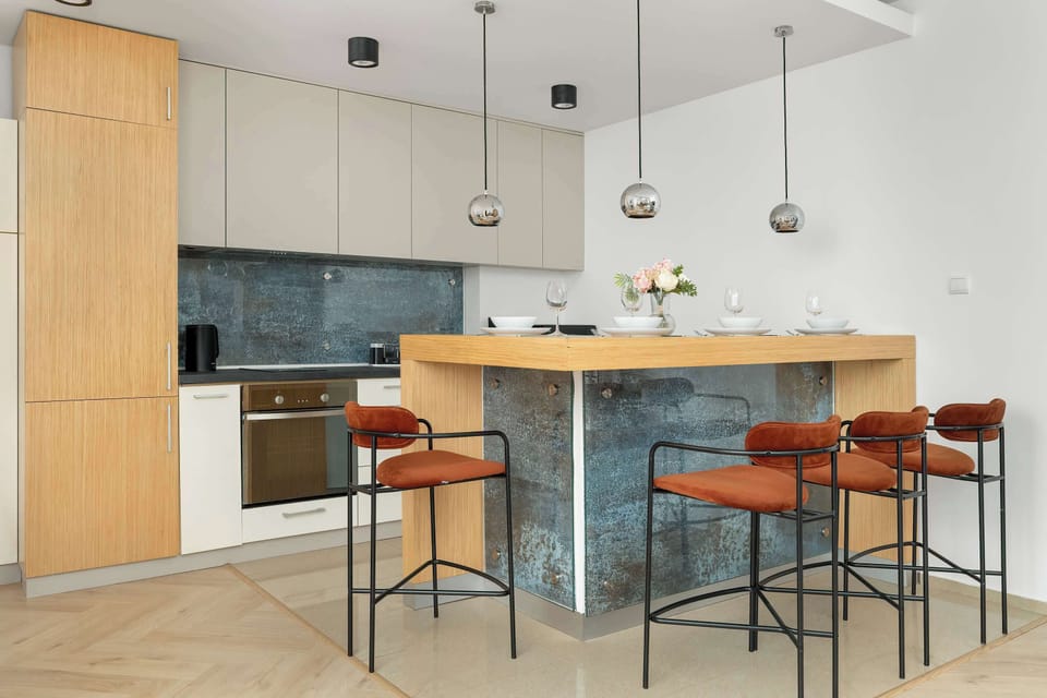 A bright open-plan kitchen with a large island featuring a stone countertop. High stools surround the island, blending functionality and modern design.