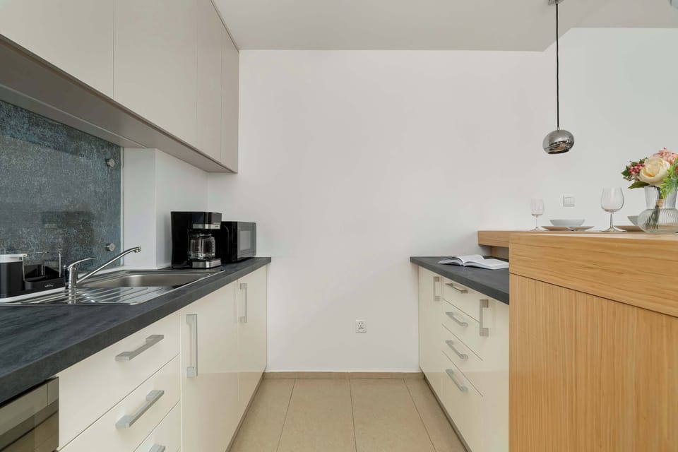 Another view of the kitchen showing its spacious layout. The wooden dining table and chairs create a balanced contrast with the modern appliances.