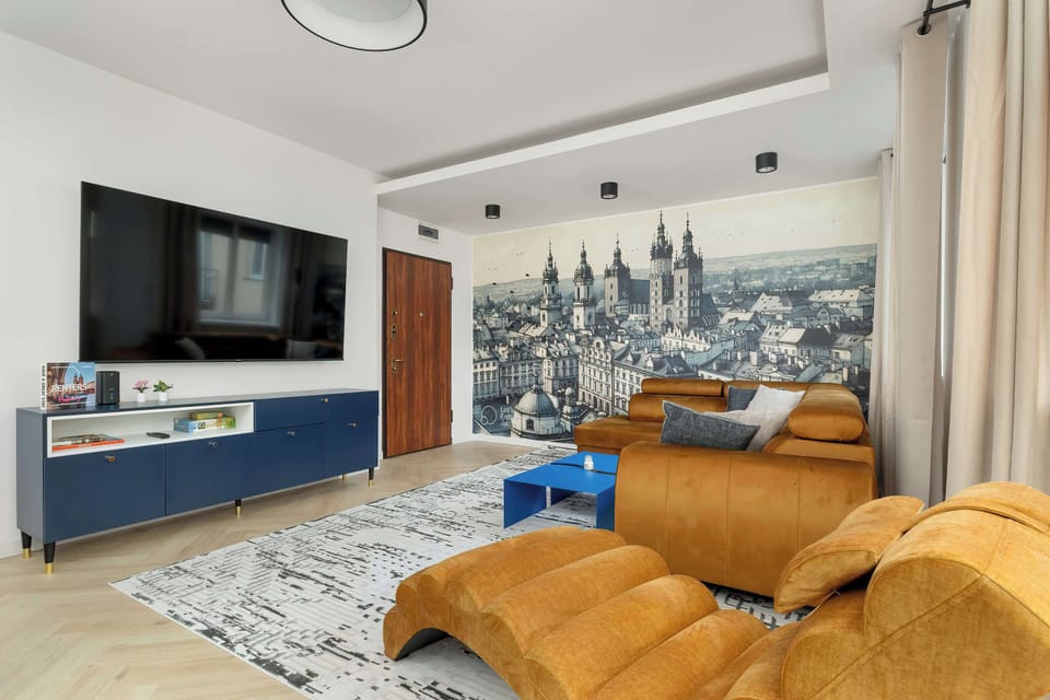 A cozy living room featuring a mustard-colored sectional sofa, a modern TV mounted on a wall, and a contemporary fireplace. The walls are adorned with unique decorative panels, creating a warm ambiance.