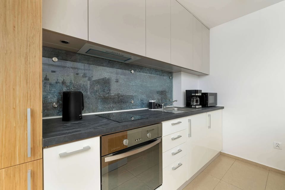A contemporary kitchen featuring clean white cabinetry, modern appliances, and a sleek countertop. The backsplash is tiled with a subtle pattern, adding a hint of character.